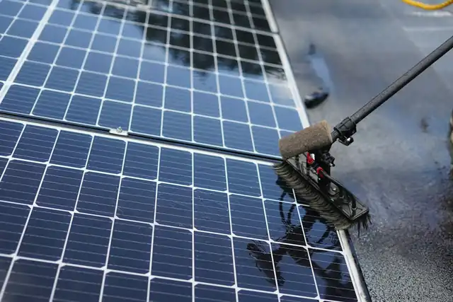 Solar panels being cleaned with a long-handled brush