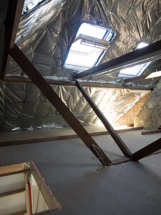 A loft space with exposed rafters and foil insulation