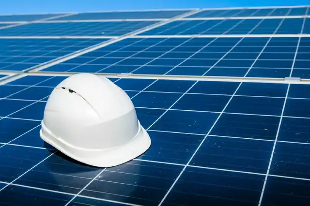 A white safety helmet resting on solar panels